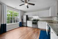 Clean and functional kitchen with granite countertops, stainless steel appliances, and plenty of cabinet space. A large window lets in natural light and overlooks the backyard with easy access to the deck—perfect for indoor-outdoor flow.