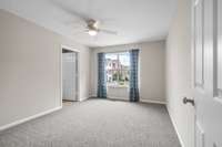 Spacious upstairs bedroom with new Berber carpet, neutral walls with fresh paint, and a large window that brings in natural light and a view of the front courtyard. Features an en-suite bath and walk-in robe.