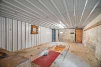 The shop has a concrete floor, electric, and a mechanic's pit/trench drain