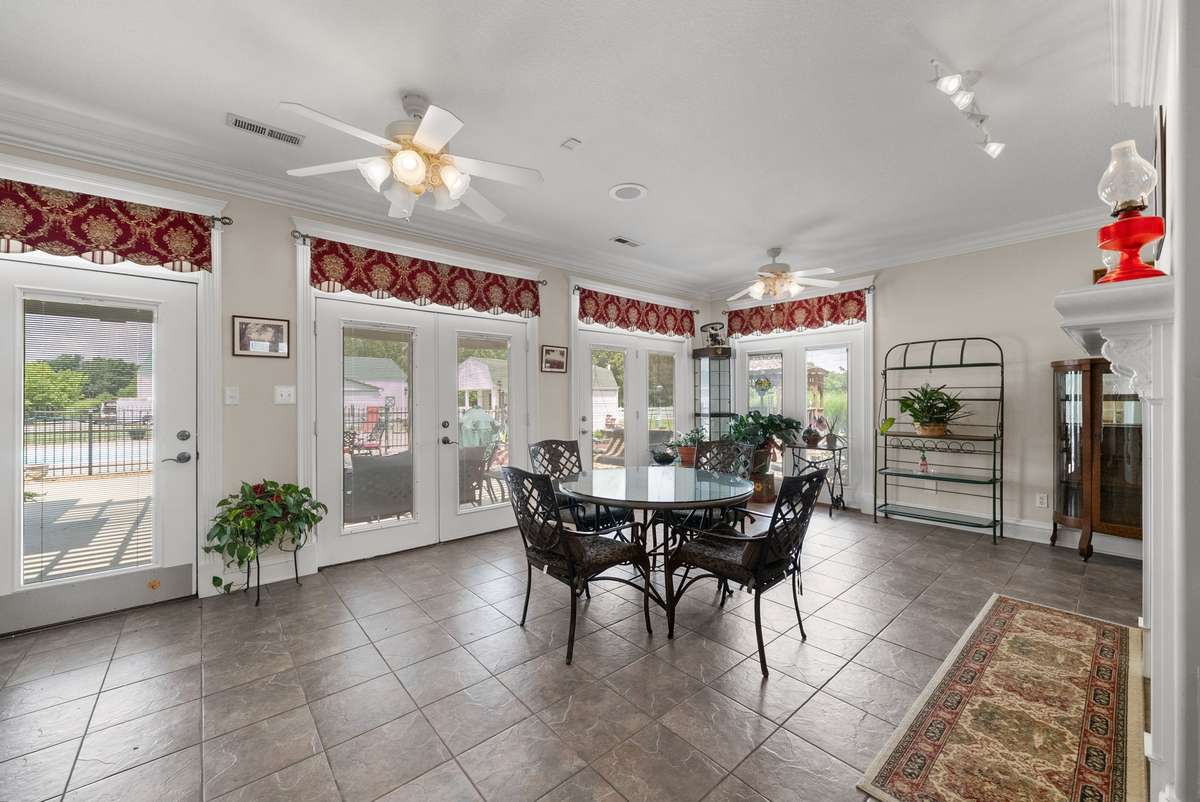This bright 14x23 Sunroom looks out onto the pergola-covered patio, outdoor kitchen and in-ground pool.