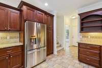Kitchen with upgraded stainless appliances, tumbled travertine backsplash and under cabinet lighting.  Large pantry storage to the right of the refrigerator (conveys with property).  Stairs to the second floor.