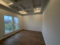 Spacious formal office with coffered ceiling and wood flooring