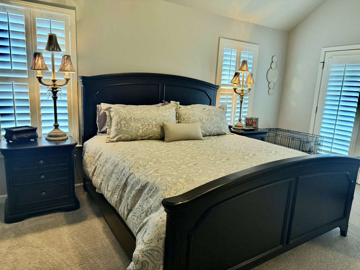 Primary Bedroom King Bedroom Suite that all stays! There are 2 Bedside Tables, Lamps, King Size Bed to include Comforter, Makeup Table, Chest with large TV on it. Also large Dog Crate and big comfy Lounge Chair in this Bedroom.