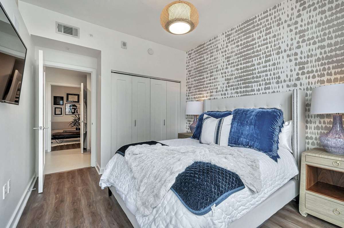Primary bedroom has elegant wallpaper and is large enough enough to accommodate a queen size bed and two nightstands. The TV wall can be used for a console, a dresser or a bench.