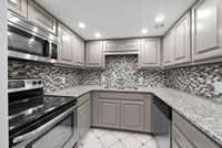 Remodeled kitchen with granite counters, stainless steel appliances, tile floors & backsplash, and a pantry.