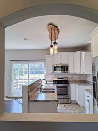This arched detail adds a touch of architectural style framing the attractive kitchen and pictuesque view to the back acreage.The pass through opening is both functional and beautiful.