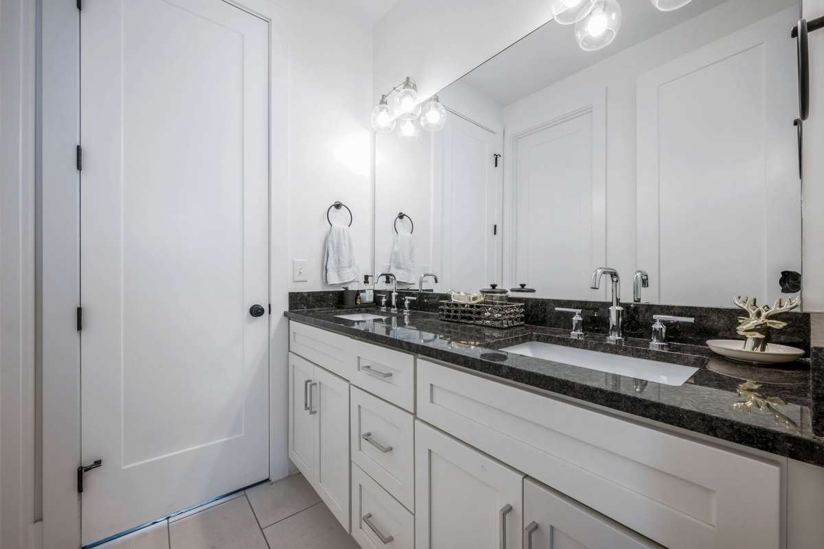Ensuite bath for Bedrooms #2 & #3--dual vanity sink and black granite countertop set against white shaker style cabinets for clean lines.