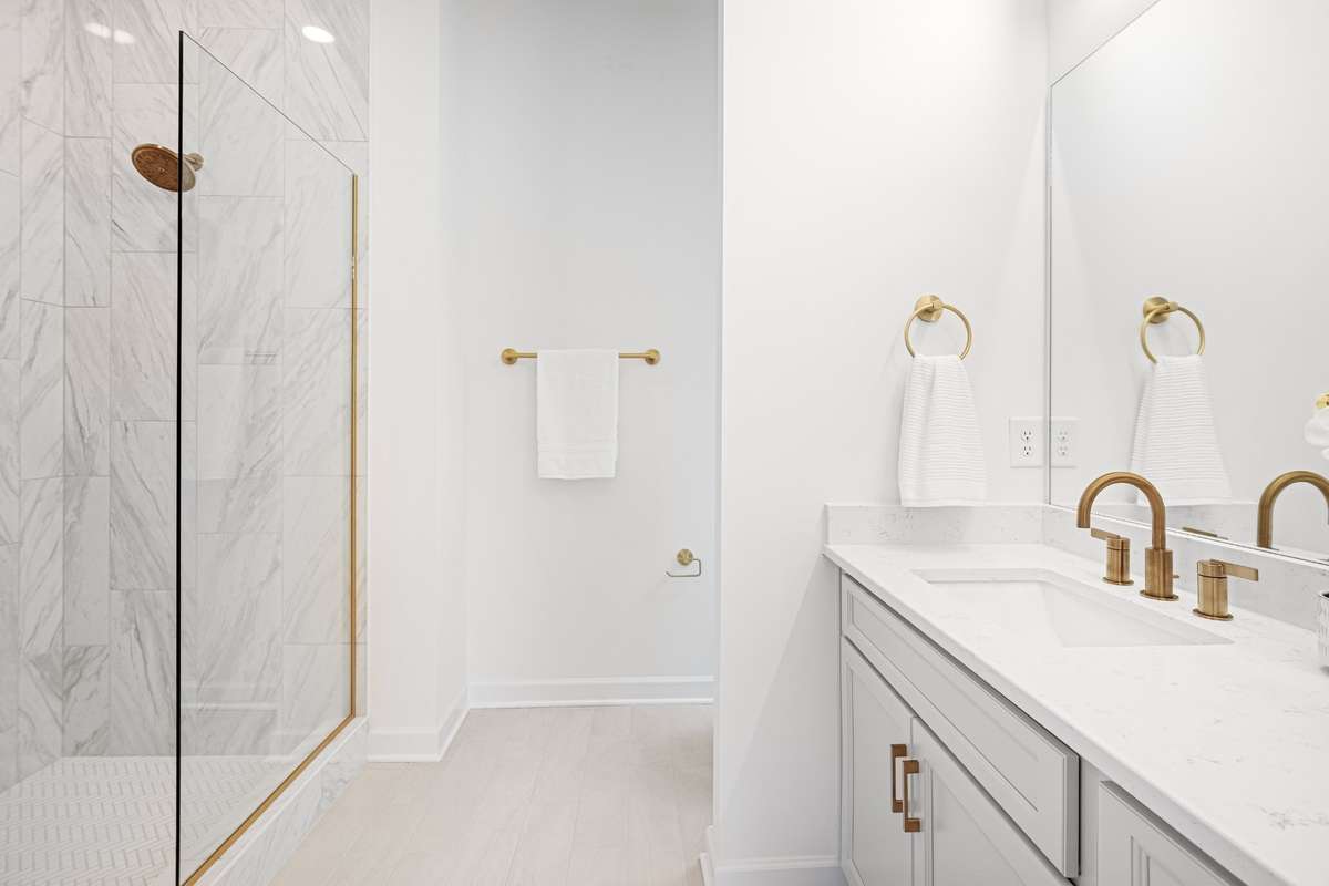 Frameless glass shower with mosaic tile flooring and floor to ceiling wall tiles
