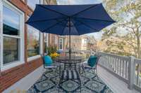 An inviting outdoor perch features a table with an umbrella, providing the perfect spot to relax and enjoy breathtaking views of the lush greenery and expansive backyard.