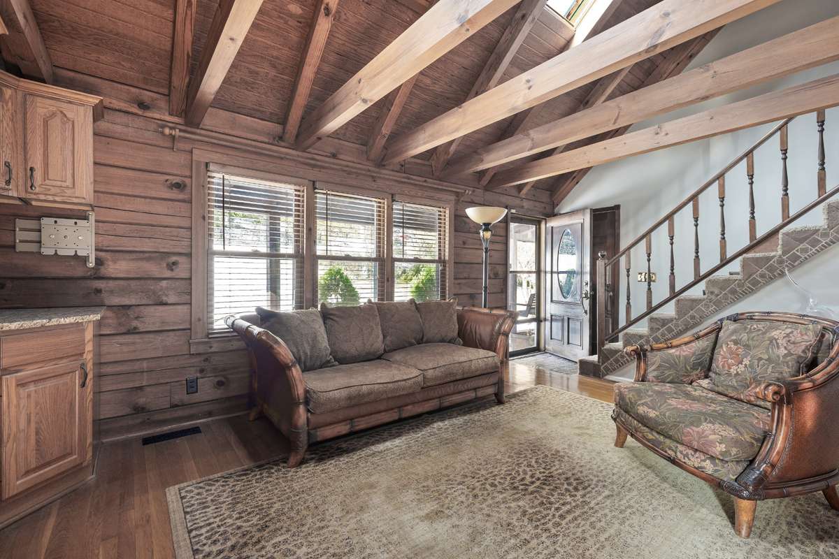 Another view of the great room, featuring hardwood floors and a charming log cabin ambiance. Freshly painted throughout as of 12/30/2025.