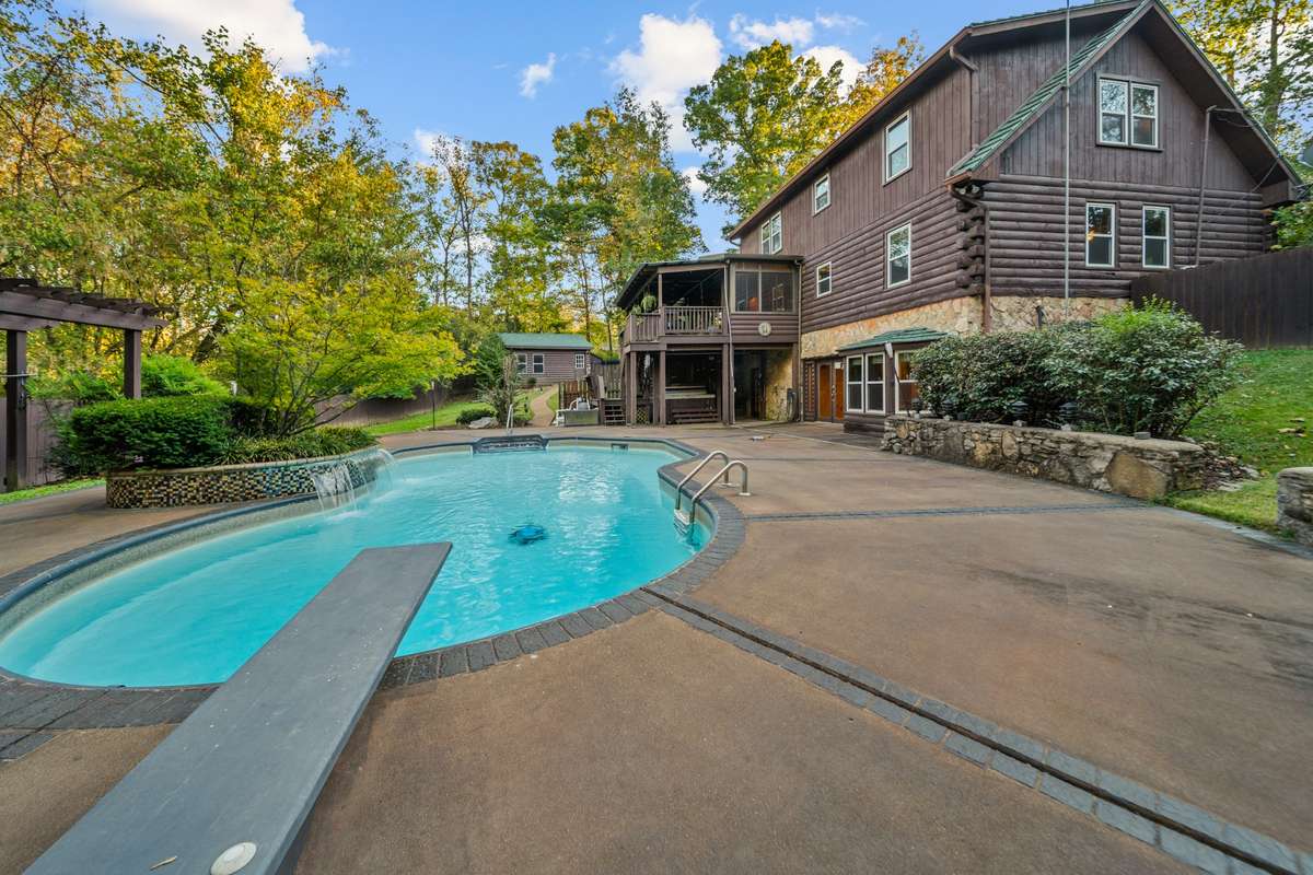 Backyard perfection with lush landscaping, a waterfall, and diving board for endless fun, all surrounded by mature trees for privacy and serenity!
