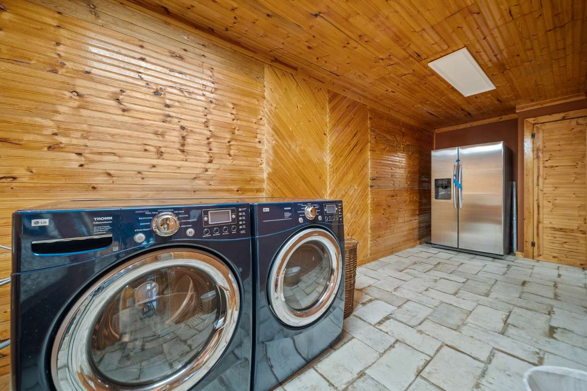 Laundry room with a generous layout, stone sink, and space for added shelving. (Washer, dryer, and refrigerator not included.)