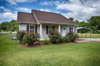Front of house- concrete sidewalk and driveway, detached carport, covered front porch with home entry, simple landscaping