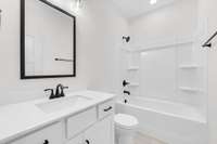 Second full bathroom with white cabinets, marble tops and tile flooring