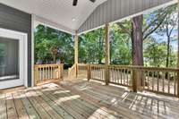 Peaceful covered back deck with ceiling fan overlooks the .63 acre lot with mature trees