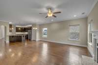 Unstaged image of the living room looking back towards the kitchen and entry foyer.  The pantry is visible just to the right of the INCLUDED fridge in this photo.