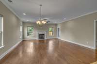 Located directly through the entry foyer, the large living room has crown molding, beautiful floors, and an easy to use gas fireplace. The door just to the right of the fireplace in this photo leads to the screened in back porch.