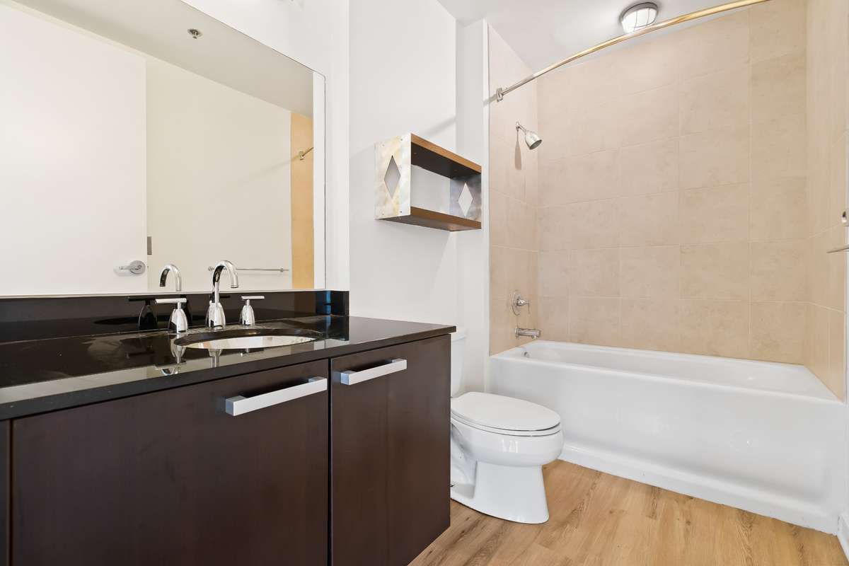 Guest Bathroom with black granite countertop, stainless steel sink bowl and tub/shower combination. Located adjacent to Guest Bedroom and opens to the main living area of condo.