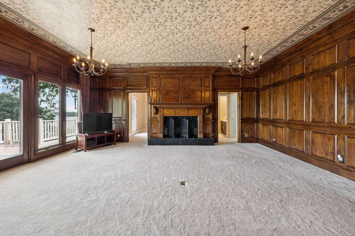 Den has cherry walls, fireplace and cozy carpet.