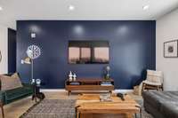 The 65" Roku TV is complimented by a modern and sleek entertainment station table and the acacia wood coffee table. The green velour reading chair adds color and texture to contrast, yet blend with the charcoal gray faux leather sectional sofa.