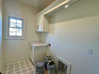 Laundry room w/hanging rack & custom cabinets for storage. Folding table