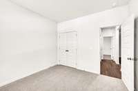 Comfortable secondary bedroom with neutral tones, plush carpet, and a double-door closet.