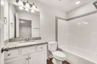 Upper-level bath with granite vanity, brushed nickel fixtures, and a tiled shower surround—perfect for guests or a private suite feel.