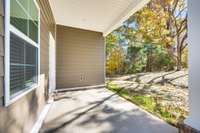 Enjoy the covered patio with peaceful wooded views — an inviting outdoor space that could easily be transformed into a screened porch.