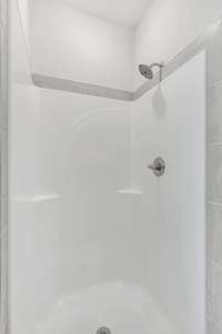 Step into the sleek walk-in shower featuring a clean, modern surround with subtle tile accents—easy to maintain and designed for everyday comfort.