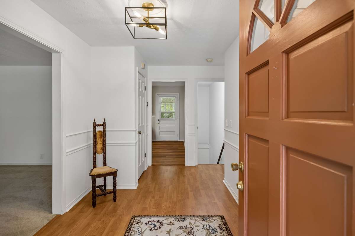 Step into a bright and airy foyer adorned with timeless wainscoting and a contemporary geometric chandelier. It flows effortlessly into the heart of the home, creating a sense of spaciousness throughout the home.