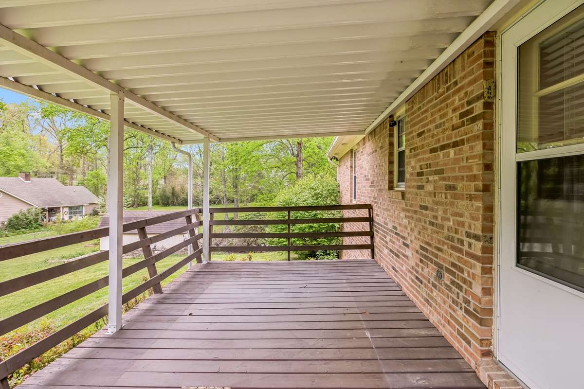 Step out of the kitchen and onto the serene covered deck, a peaceful sanctuary where you can enjoy your morning coffee while overlooking the lush, rolling greenery of the private backyard.