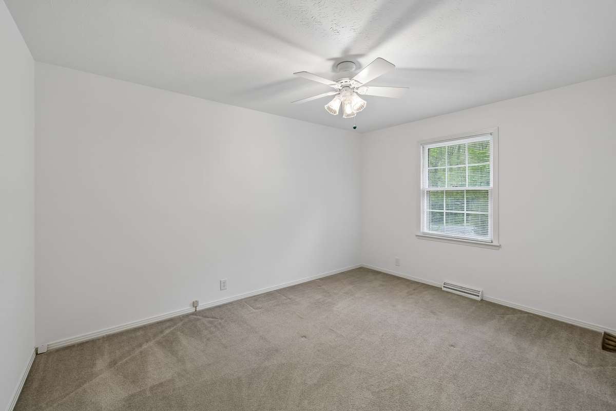 The front corner bedroom offers a quiet alcove for rest, featuring soft neutral tones. Create an inviting guest room or quiet home office.