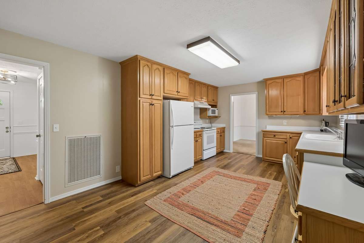 Preparing meals is a breeze in this functional kitchen, complete with crisp white countertops and appliances, ample workspace, and extra cabinet space.