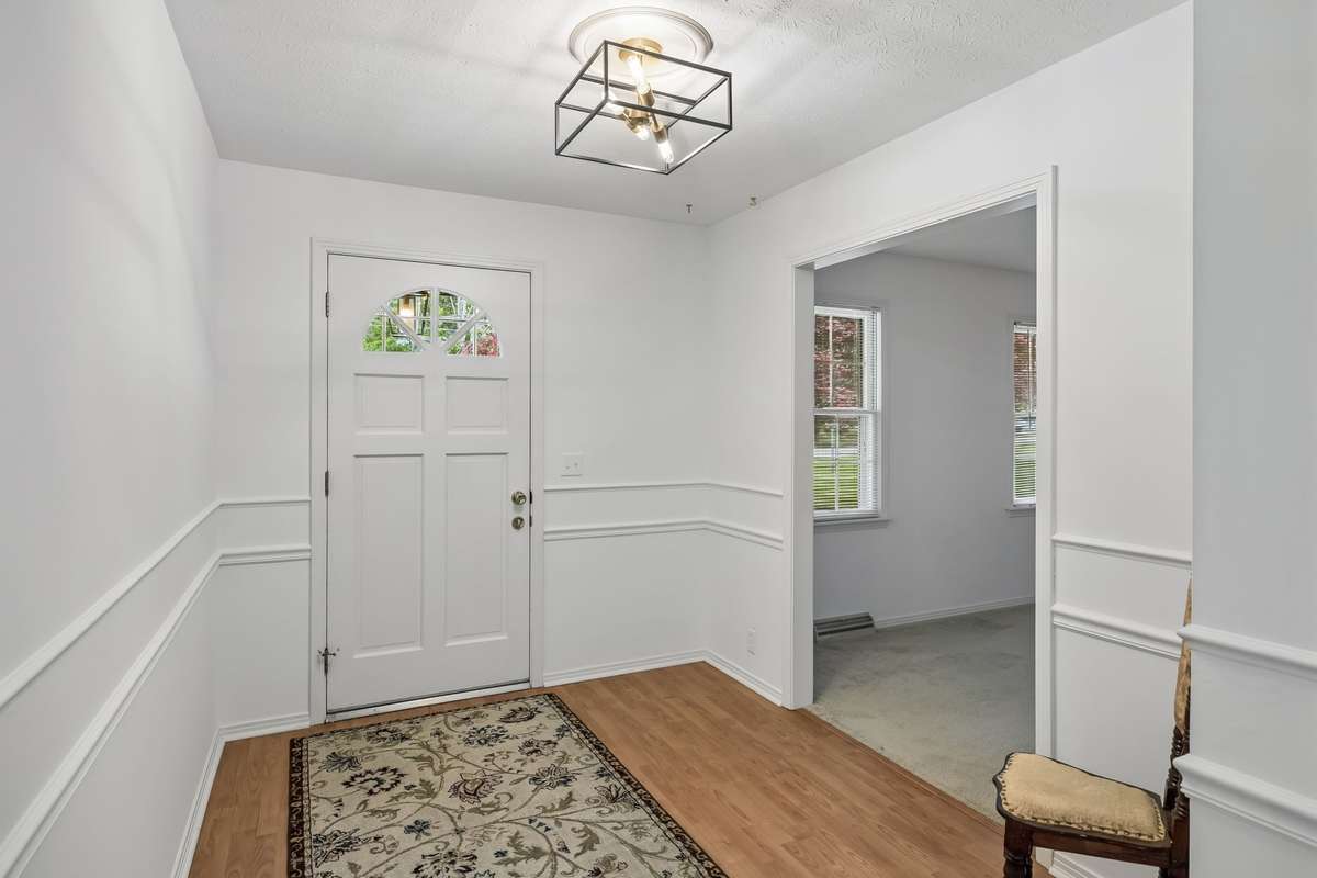 The bright and airy foyer makes a great first impression with its clean white walls, wainscoting, and modern lighting.