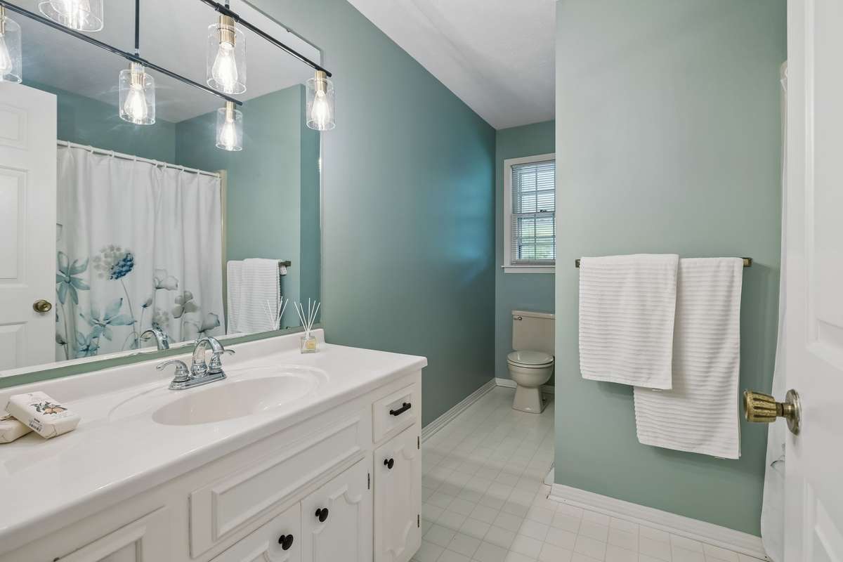 Just down the hallway, refresh and rejuvenate in this sophisticated bathroom, featuring tranquil sea-glass walls and updated hardware.