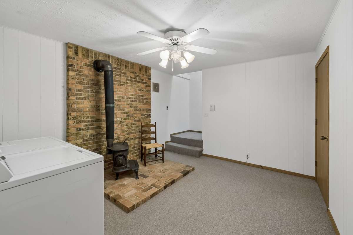 The basement level features a dedicated laundry room with a charming Franklin stove, a massive family room, half bath, and extra space for an office or private studio.