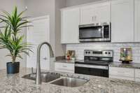 The stainless steel sink pairs beautifully with quartz countertops and white cabinetry, combining timeless design with practical function at the center of the kitchen.