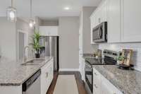Sleek stainless steel appliances pair perfectly with quartz countertops and white cabinetry—bringing both beauty and function to this modern kitchen.