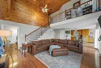 Interior of guest house with main level primary bedroom, main level garage, spacious living room is open to the kitchen, and catwalk leading to two upstairs bedrooms and full bathroom.