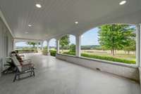 Arched openings frame stunning countryside views of the property from the expansive wraparound porch, which connects to the kitchen.