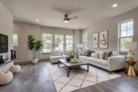 Main Living Room with amble natural light and extra windows, overhead lighting, ceiling fan, and wood flooring.  **This photo is virtually staged**