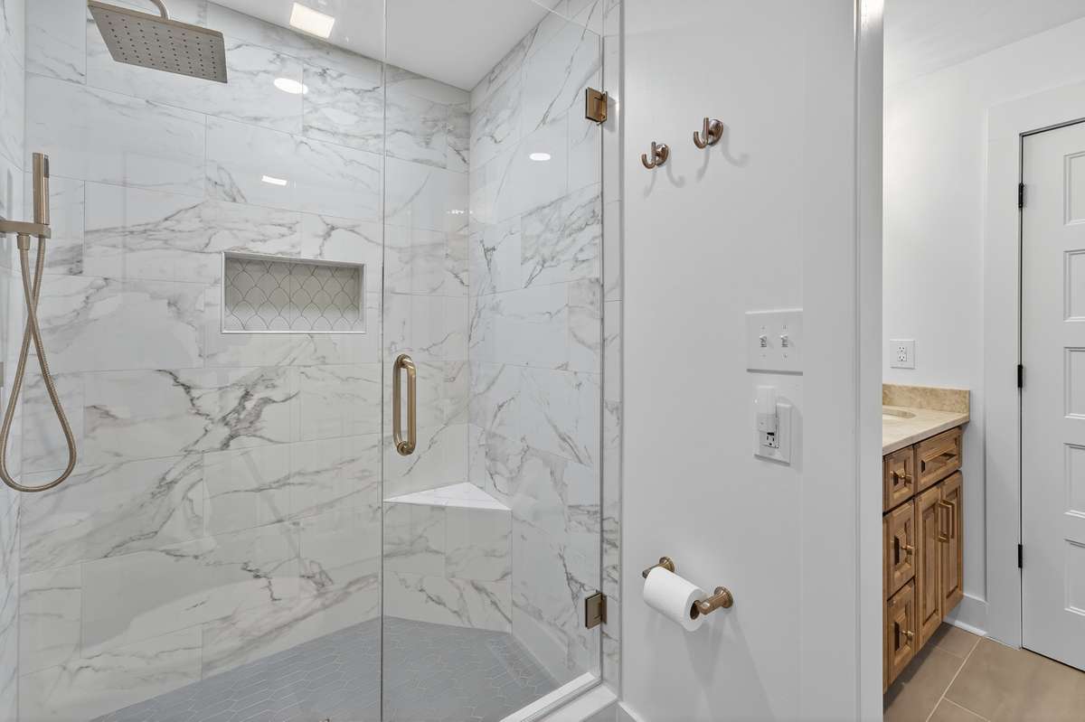 Primary shower is one to envy! Gorgeous full tile shower accented with champagne bronze hardware and frameless glass enclosure. The rain head shower head is relaxing and shower also features a handheld sprayer.