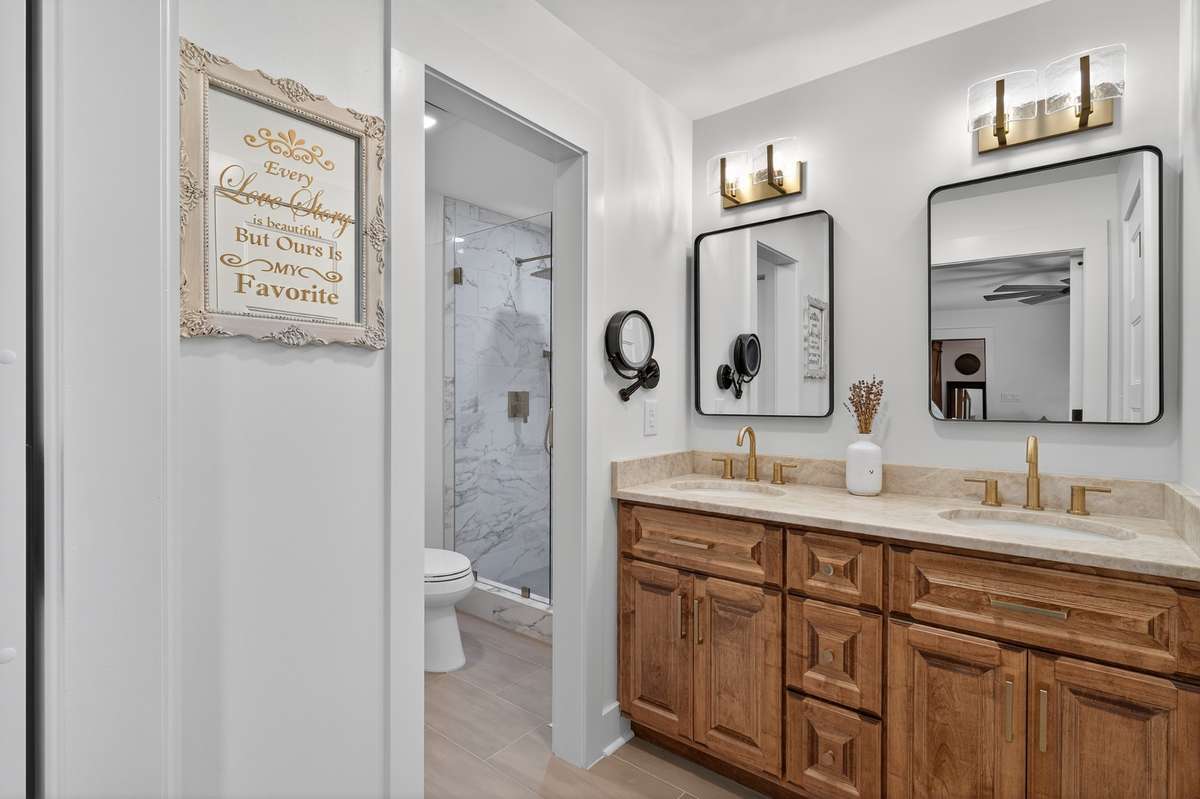 Primary bathroom has a custom made all wood vanity with quartzite Taj Mahal leathered finish countertops accented with champagne bronze hardware.