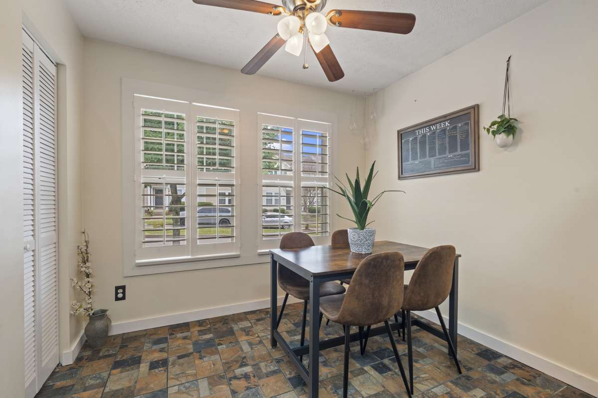 The dining area is complete windows with stunning plantation style shutters and an overhead ceiling fan .
