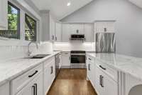 Renovated kitchen with stainless appliances, beautiful hardwood floors, tile backsplash, and gorgeous island. (pic from prior listing)