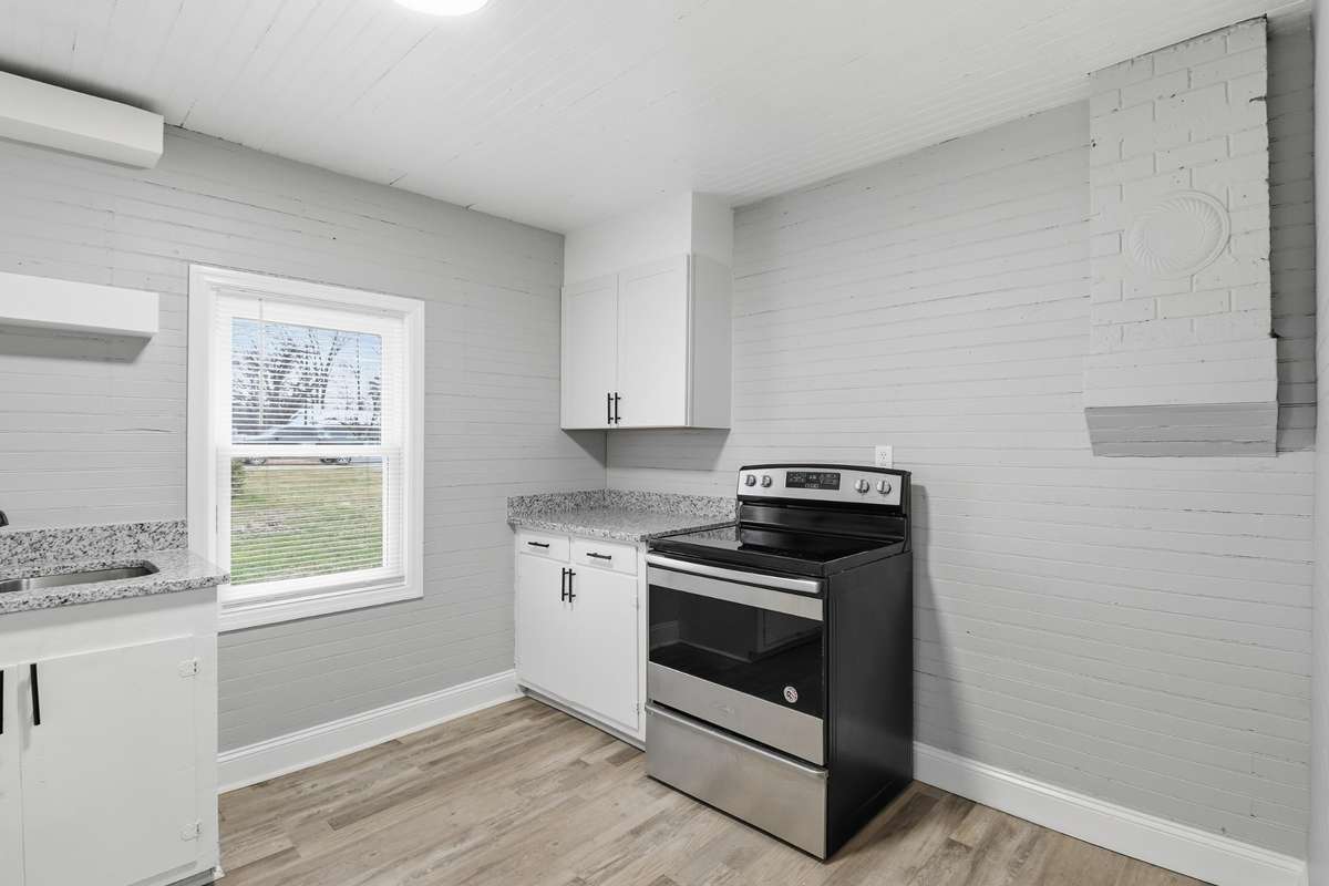 The kitchen has new upper cabinets, shelves, stove, sink, granite counter tops, and LVP flooring.