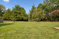 Backyard view featuring mature trees and lush landscaping.