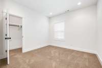 Bedrooms 3 and 4 complete the upstairs, along with a third full bathroom. Pictured here is bedroom 3 with a walk-in closet, unfurnished.