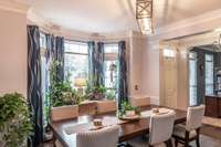 The formal dining room features lots of natural light, updated fixtures, custom millwork, and hardwood-style tile floors!