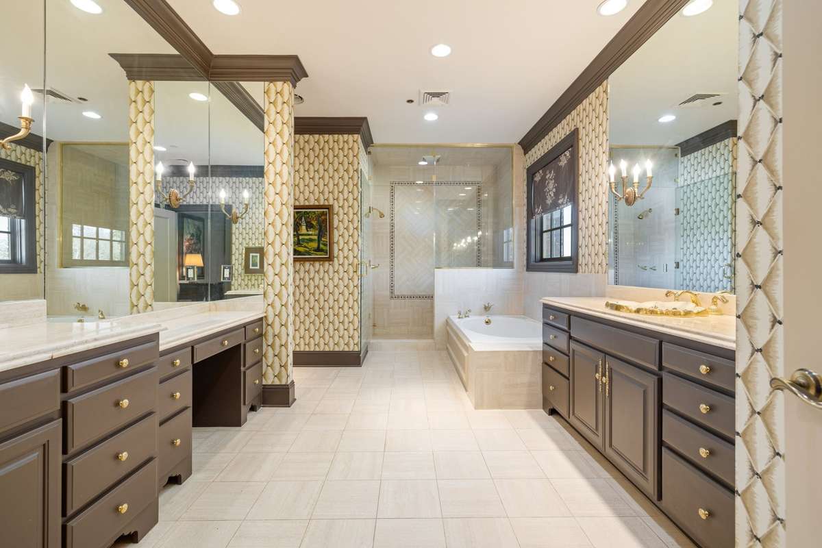 Abundant space and storage are hosted in this primary bathroom with two vanities and walls of mirrors.
